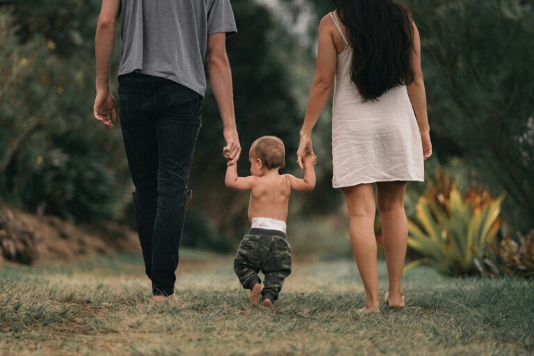 Papás con su bebé en brazos disfrutando al aire libre, símbolo de estabilidad patrimonial y ahorro con propósito